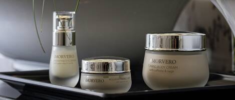 A bathroom vanity with a sink, two Morvero body cream containers, and a vase with white flowers.