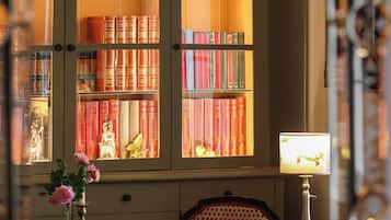 Una habitación con una amplia estantería llena de libros, un escritorio con lámpara y una silla.