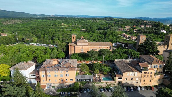 An aerial view of a historic town with a prominent church, residential buildings, and a well-maintained park. - Hotel Vannucci (Citta della Pieve)