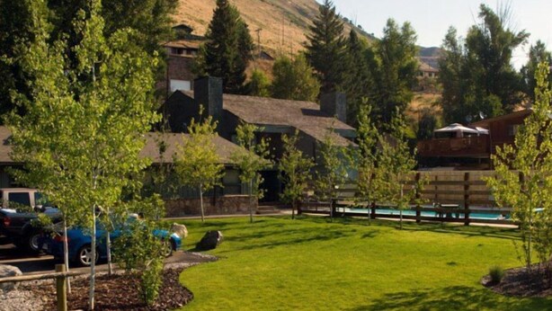 A residential area with a grassy lawn, a wooden deck, and a swimming pool. - Pony Express Motel (Jackson)