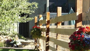 A wooden fence with lattice panels, a grassy lawn, and hanging flower baskets. - Pony Express Motel (Jackson)