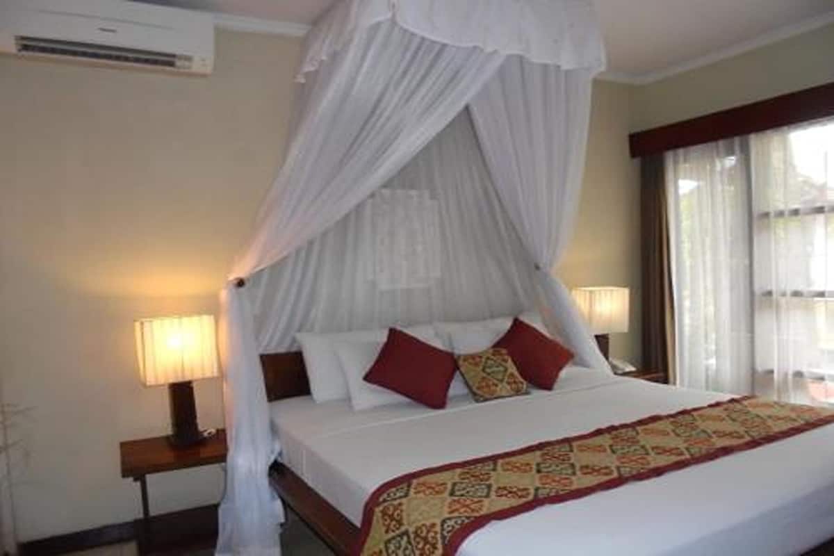 A bedroom with a four-poster bed, a canopy, and a patterned throw blanket.