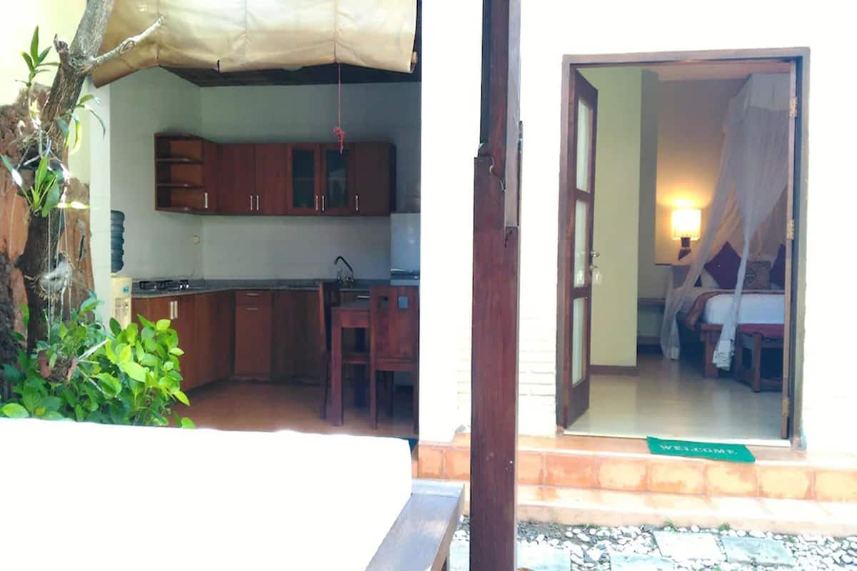 A room with a bed, a nightstand, and a window with a curtain.