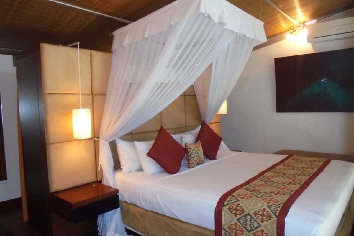 A bed with a canopy, bedside lamps, and a patterned bedspread.