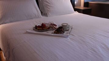 A neatly made bed with a tray of food and a cup of coffee.