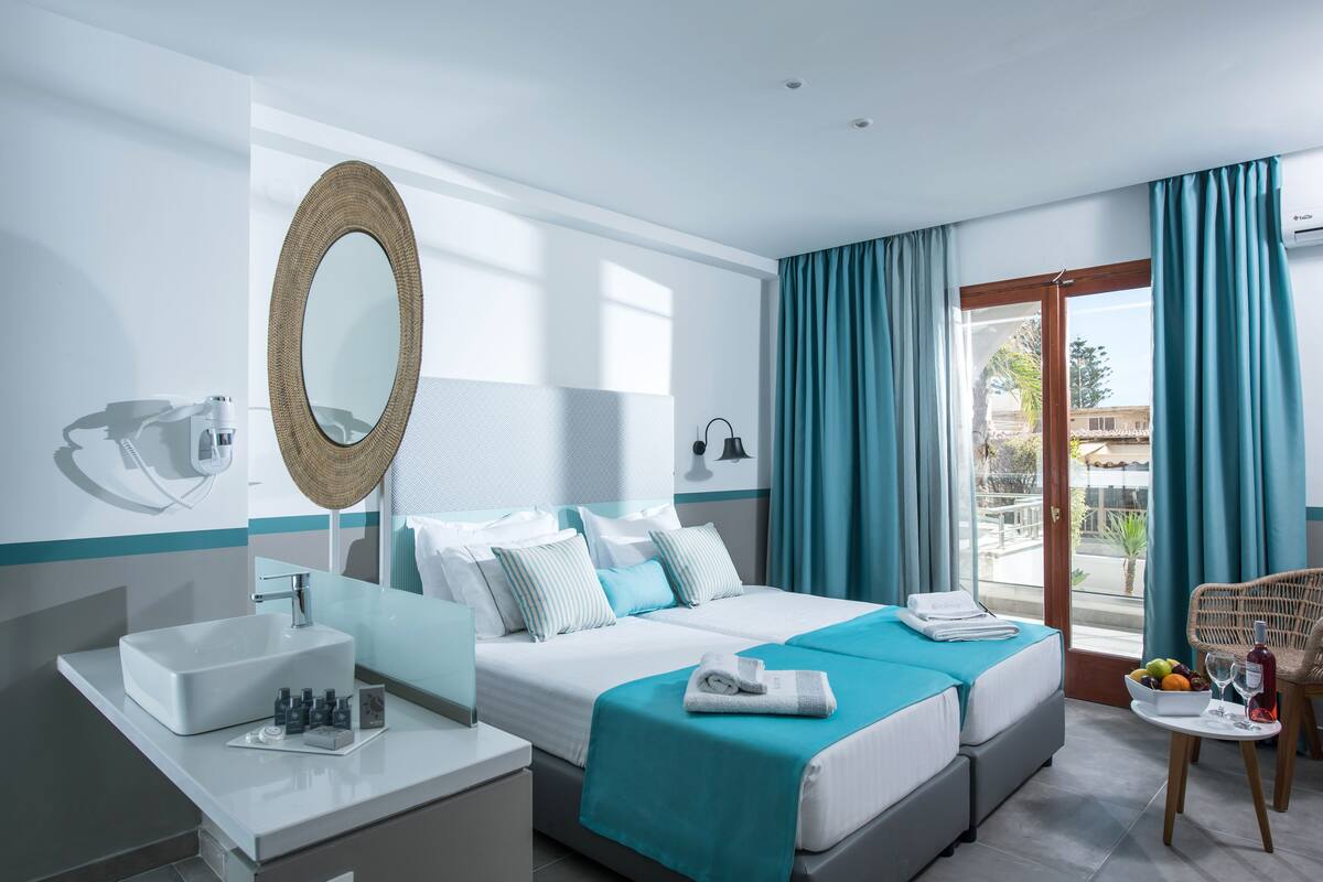 A hotel room with a large bed, a bathroom with a sink, and a view of the outside.