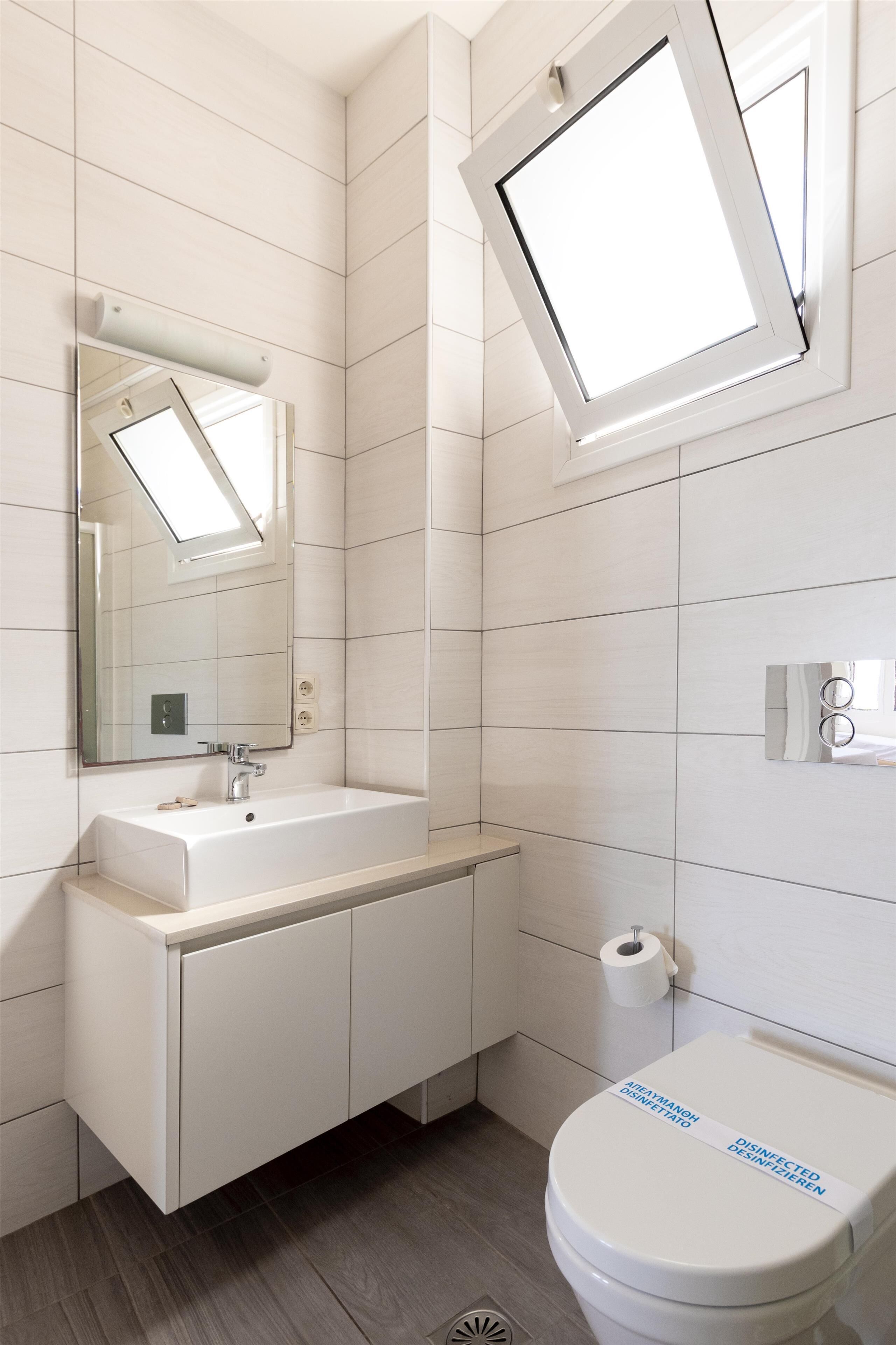 A modern bathroom with a white sink, mirror, and toilet.