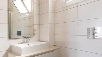 A modern bathroom with a white sink, mirror, and toilet.
