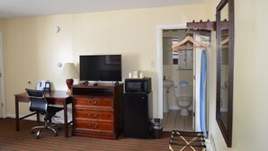A hotel room with a desk, chair, dresser, television, microwave, and a bathroom visible through an open door. - Relax Inn (Brunswick)