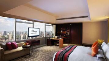 A modern hotel room with a large bed, a sofa, a desk, and a TV.