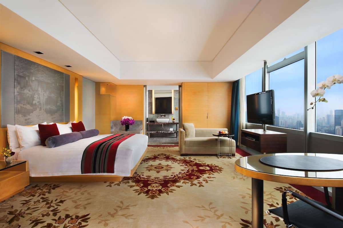 Une chambre d’hôtel moderne dotée d’un grand lit, d’un bureau, d’une chaise, d’une télévision et offrant une vue sur la ville.
