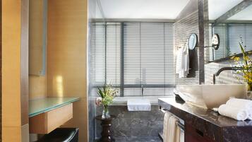 Un baño moderno con un espejo grande, una bañera y un tocador con lavamanos.