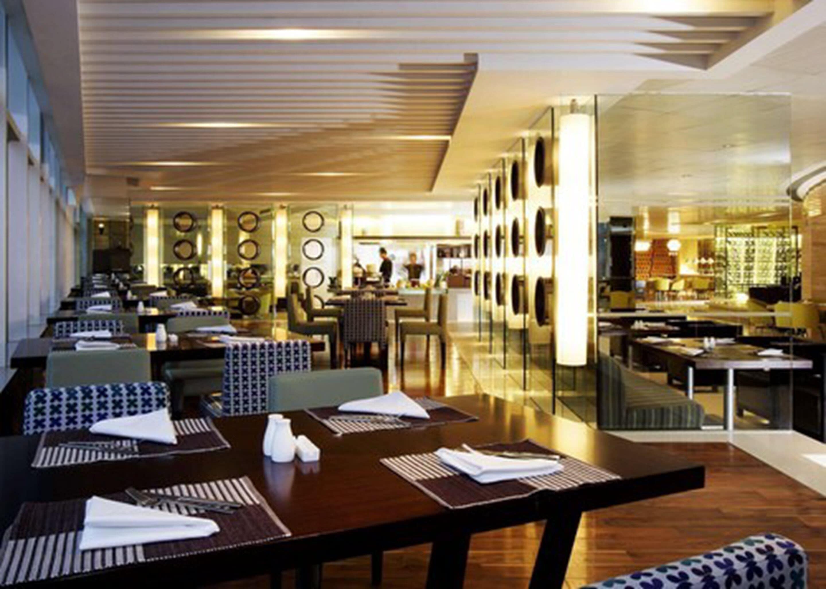 Un restaurante moderno con mesas comunitarias largas, techos altos y un interior luminoso.