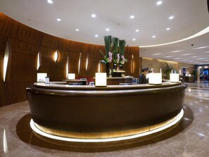 Welcome to our reception area, featuring a curved reception desk, comfortable seating, and a beautiful plant.