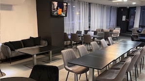A modern conference room with a long table and chairs, a sofa, and a TV screen. - Suite Home Briancon Serre Chevalier (Briançon)