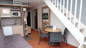 A compact living space with a kitchenette, a dining area, and a staircase. - Suite Home Briancon Serre Chevalier (Briançon)