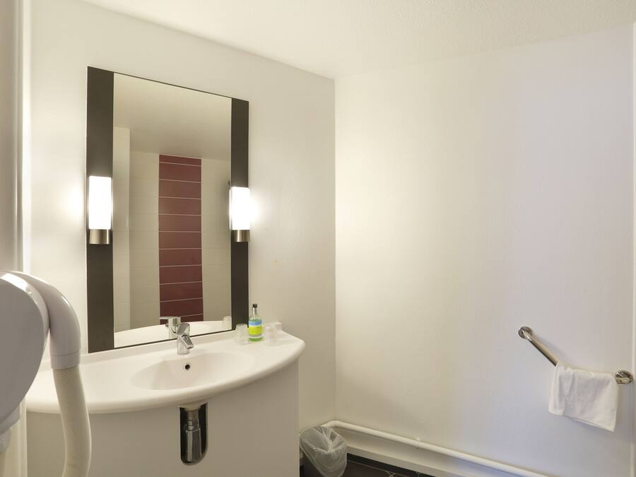 A bathroom with a white sink, a mirror, and a towel rack.