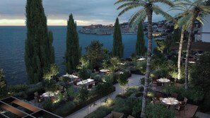 Un giardino pensile con posti a sedere all'aperto, affacciato su una città costiera e il mare.