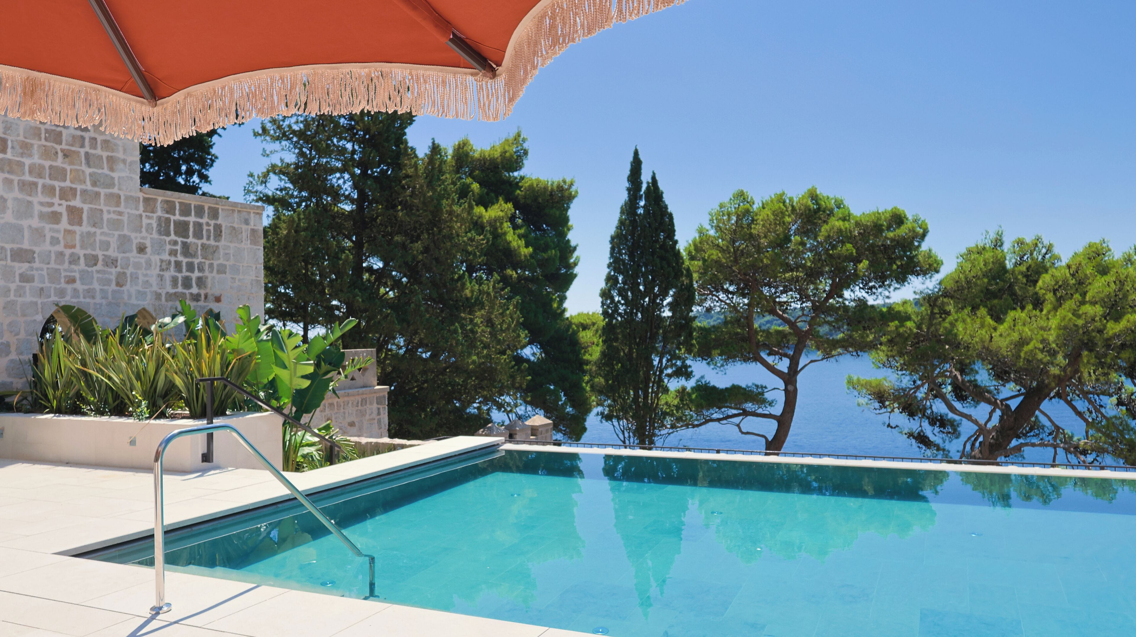 Una piscina con vistas despejadas al mar y árboles en el fondo.