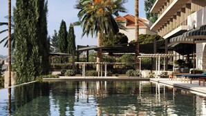 Una piscina cristalina con palmeras y un edificio de techo de tejas.