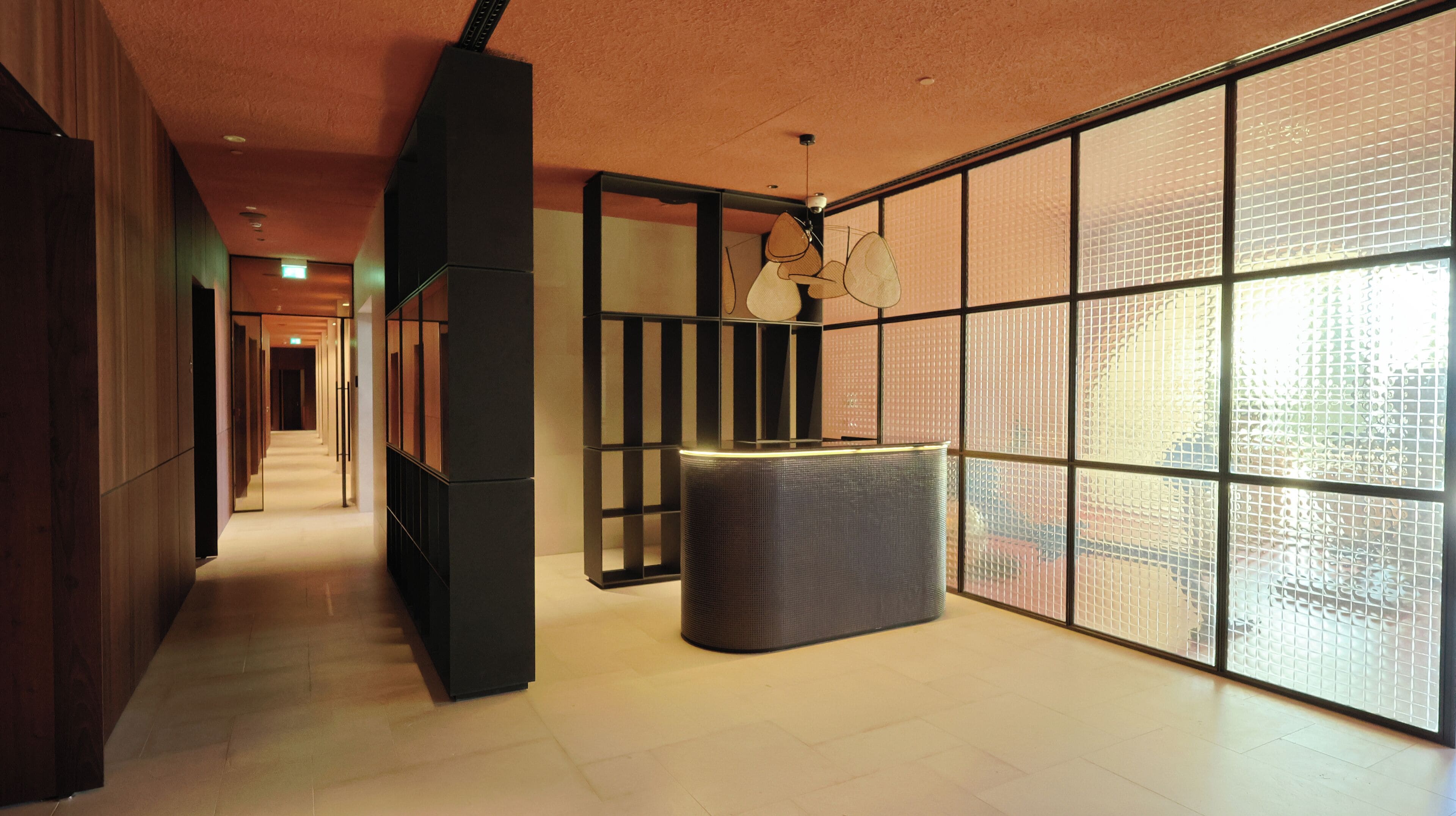 Een hal met een modern ontwerp, bestaande uit een centrale kolom, een zithoek en grote ramen met een rasterpatroon.