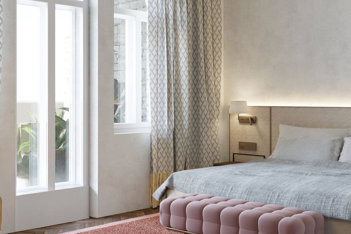 Ein Schlafzimmer mit einem großen Bett, einem Nachttisch, einer Wandlampe und einem Fenster mit Vorhängen.