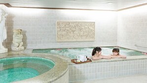 Un área de spa con un jacuzzi, una estatua y un panel decorativo.