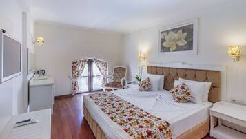 A hotel room with a bed, a chair, a desk, a lamp, and a painting on the wall.