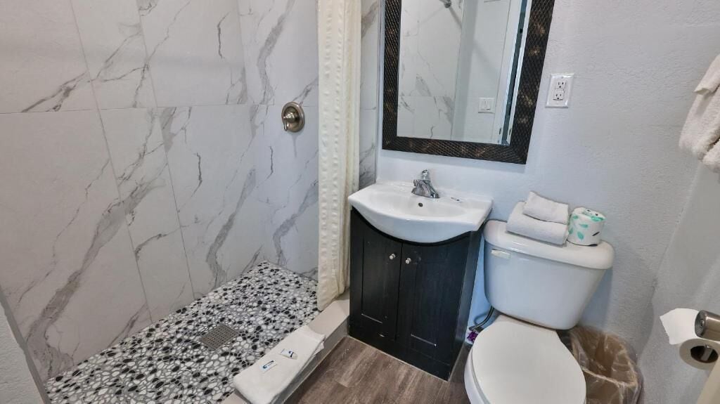 A bathroom with a marble floor, a sink, a toilet, and a shower area.
