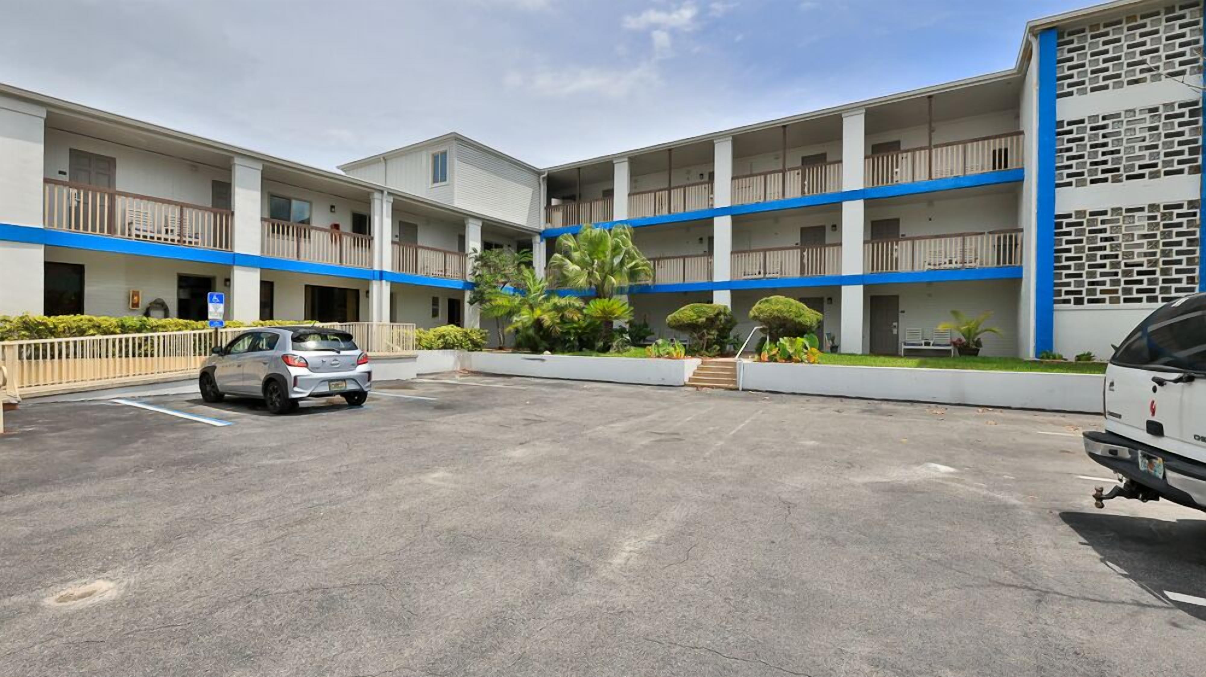 A multi-story hotel with a parking lot, a car, and a van.