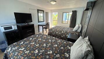 Habitación de hotel con dos camas, un escritorio, televisor, microondas y vistas al exterior.