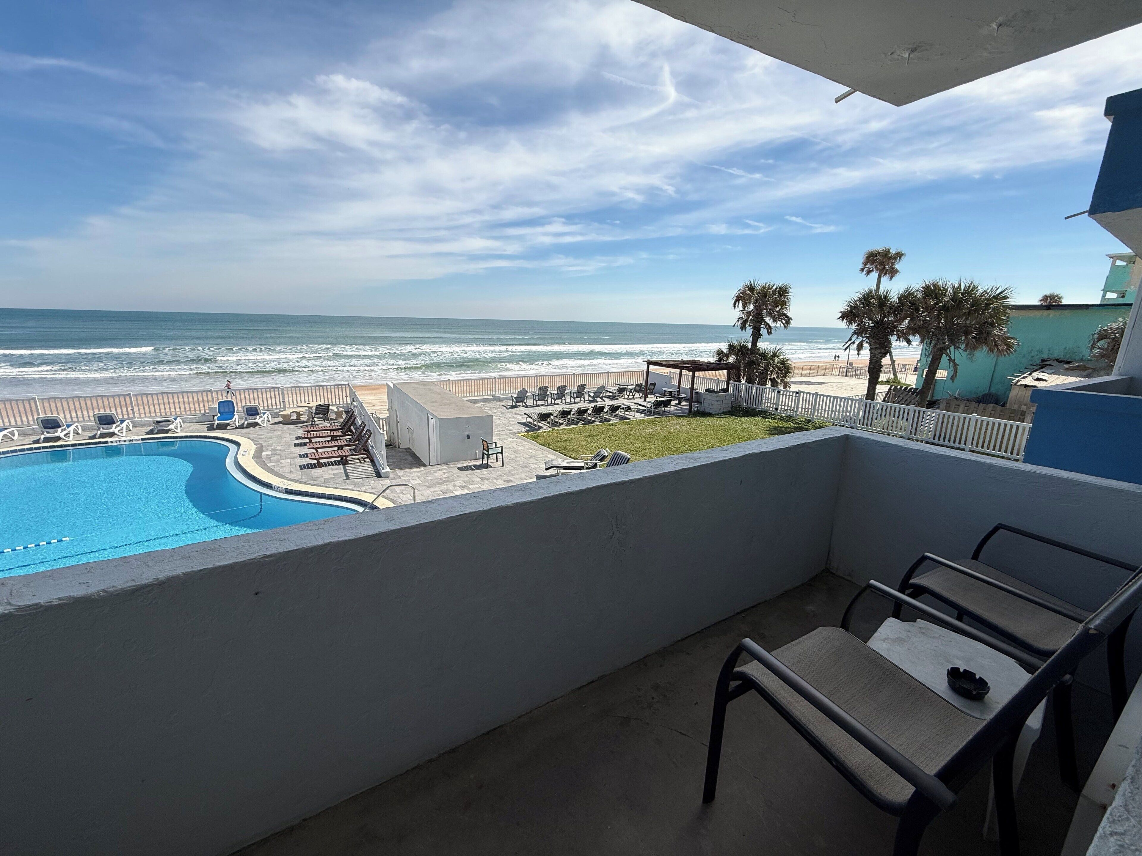 A balcony with a view of a swimming pool and beach.