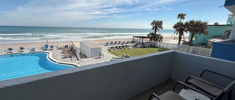 A balcony with a view of a swimming pool and beach.