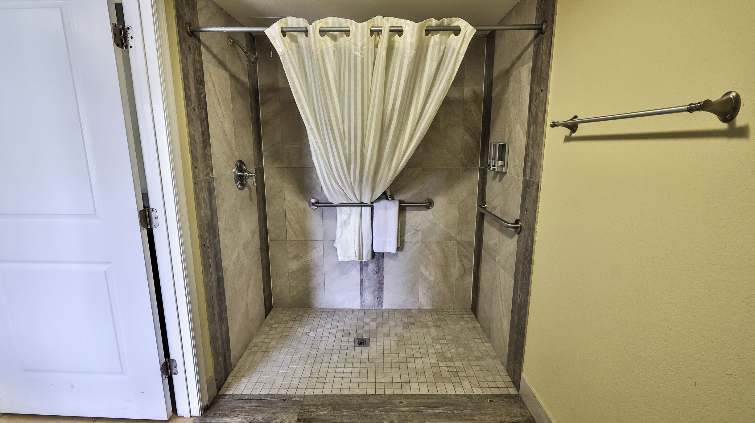 A shower with a glass door, a towel rack, and a shower curtain.