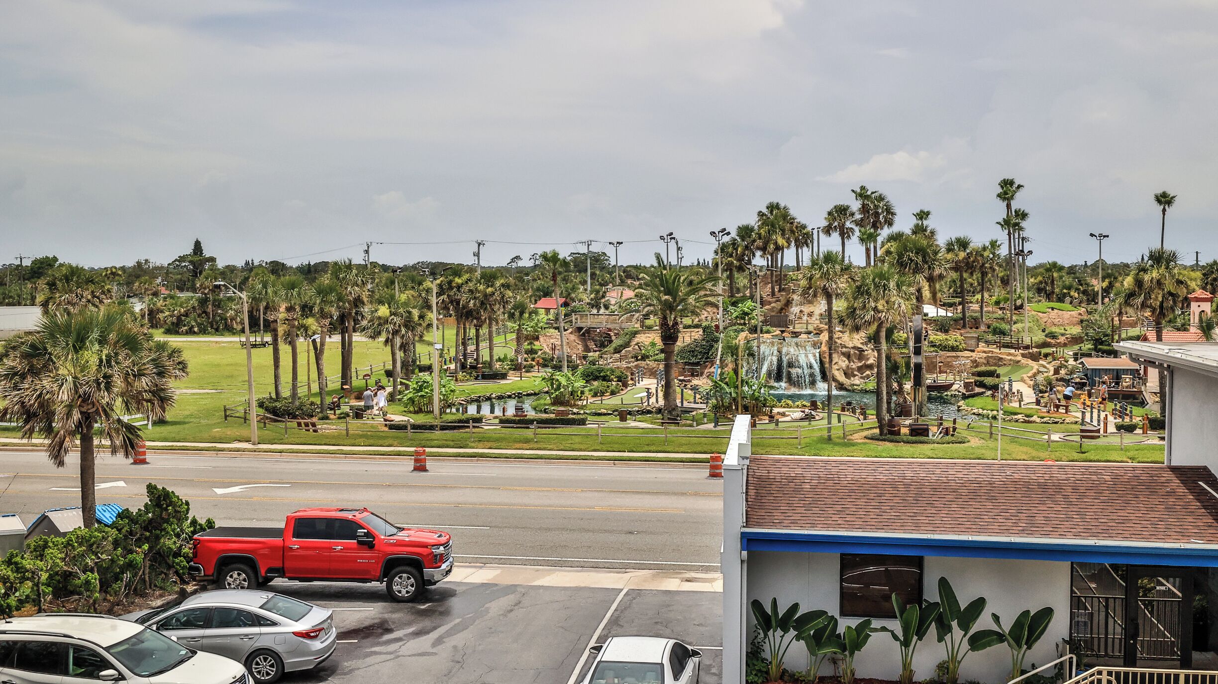 A parking lot with a red pickup truck and several cars.