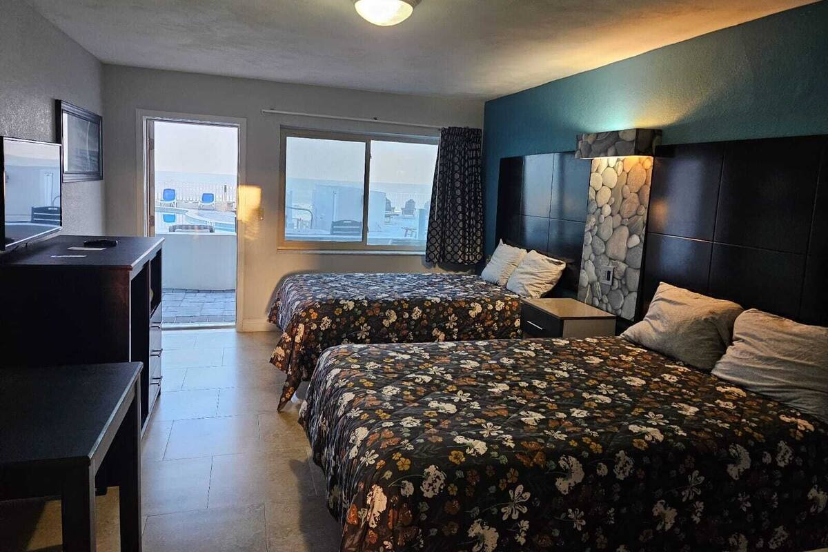 Habitación de hotel con dos camas, un escritorio, una silla y vistas a la ciudad.