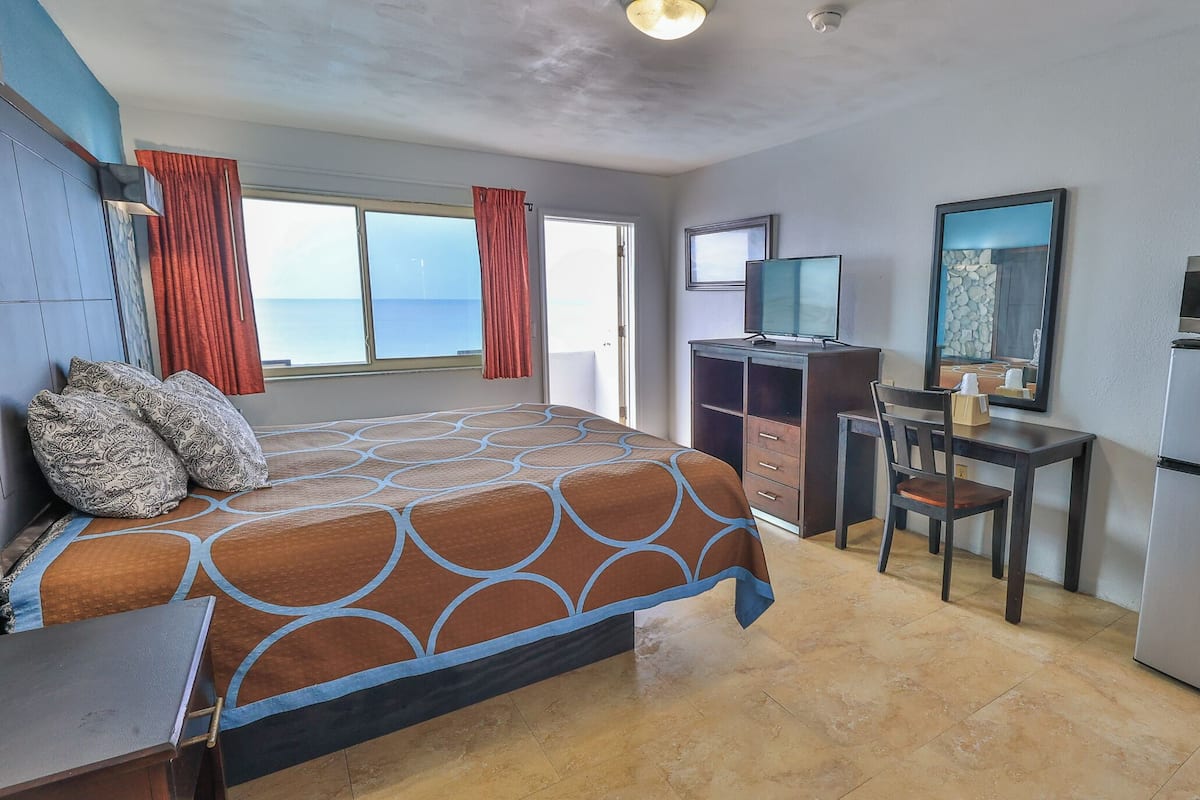 Habitación de hotel con cama, escritorio, silla, microondas y refrigerador.