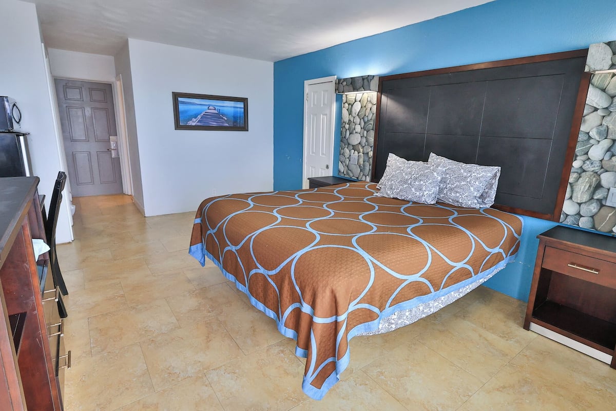 Un dormitorio con cama, mesita de noche, cómoda, escritorio y silla.