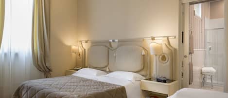 A hotel room with a large bed, bedside tables, a nightstand, and a bathroom visible through an open door.