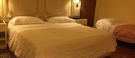 Una cama grande con cabecera, una mesita de noche y una lámpara.
