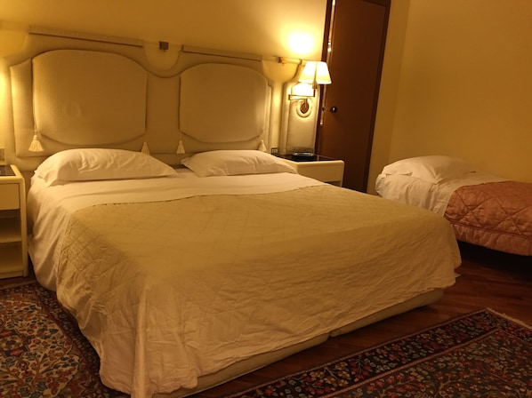 Una cama grande con cabecera, una mesita de noche y una lámpara.