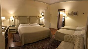Una camera d'albergo con un letto grande, due comodini con lampade, un piccolo divano e un pavimento rivestito di moquette.