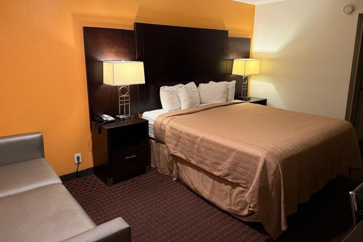 A hotel room with a bed, two bedside tables, a nightstand, and a chair.