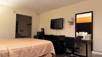 A hotel room with a bed, desk, chair, television, and a mirror.