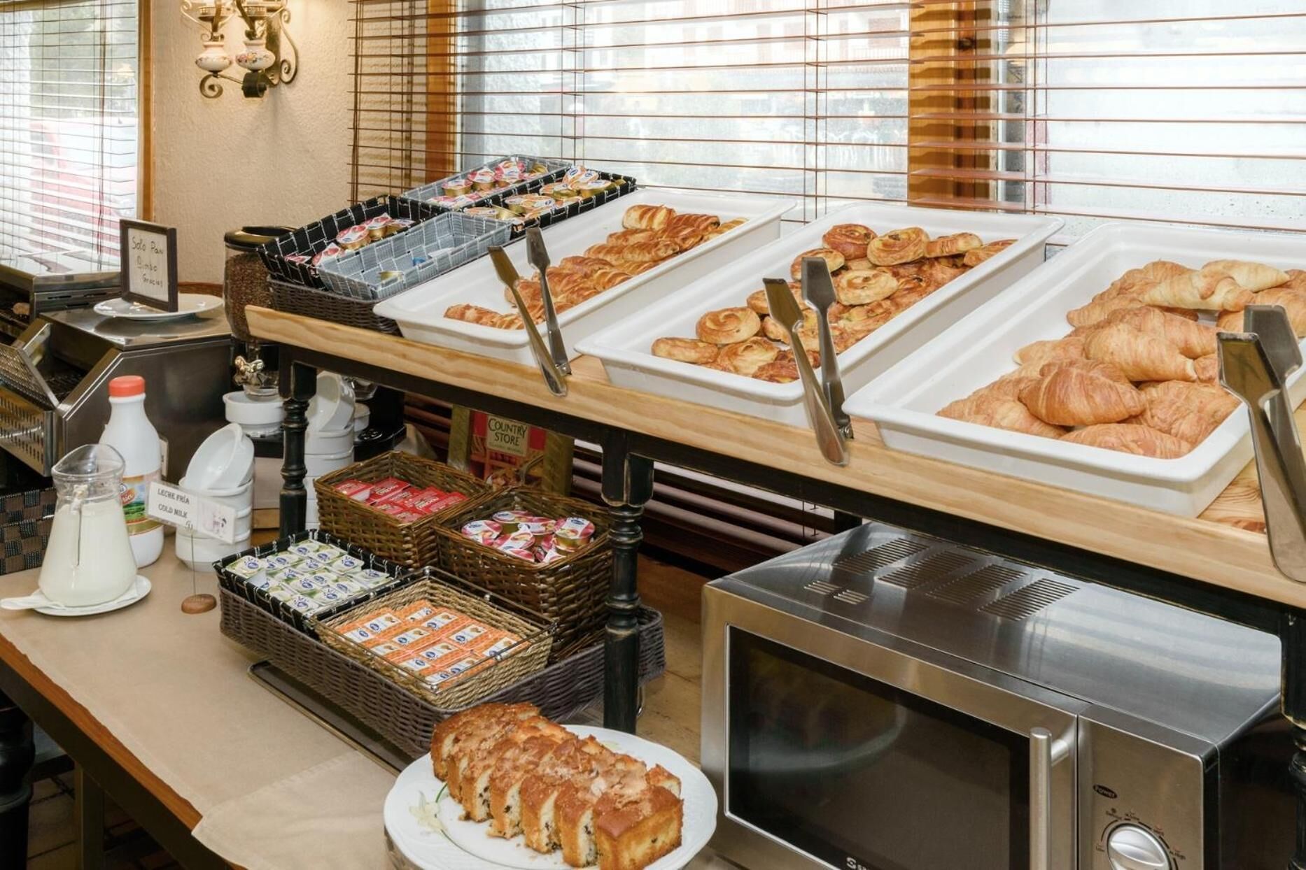 A breakfast buffet with various pastries, bread, and dairy products.