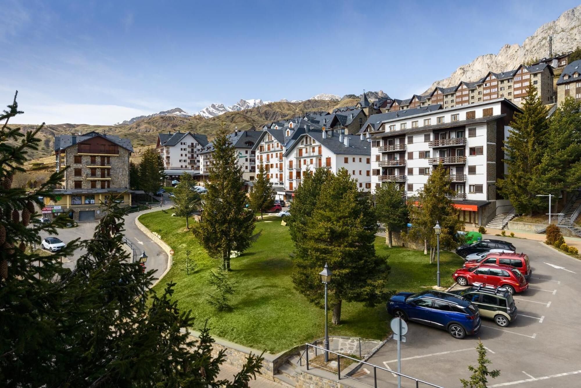 A hotel with multiple floors, a parking lot, and a mountainous backdrop.