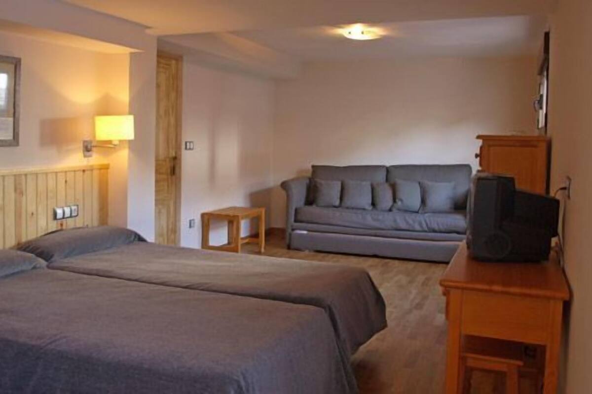 Een hotelkamer met twee bedden, een bank, een televisie en een lamp.