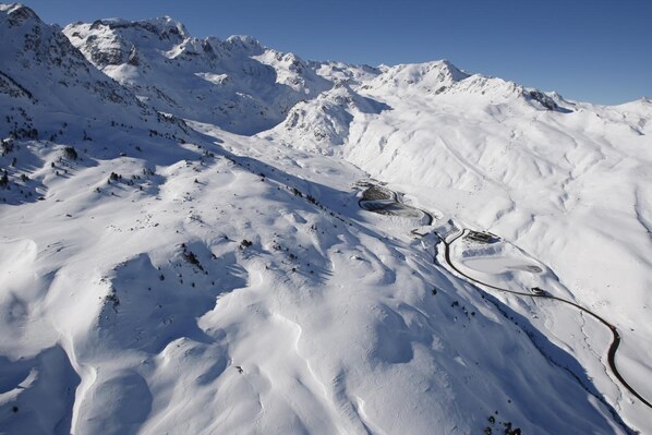 A snow-covered mountain landscape with a winding road and a small building. - Hotel Nievesol (Sallent de Gallego)