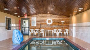 An indoor swimming pool with wooden walls, a lifebuoy, and plastic chairs. - Rodeway Inn Milford (Milford)