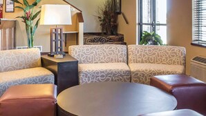 A living room with patterned sofas, a round coffee table, and leather ottomans. - Rodeway Inn Milford (Milford)